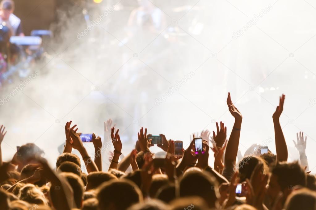 People taking photographs with touch smart phone during a music 