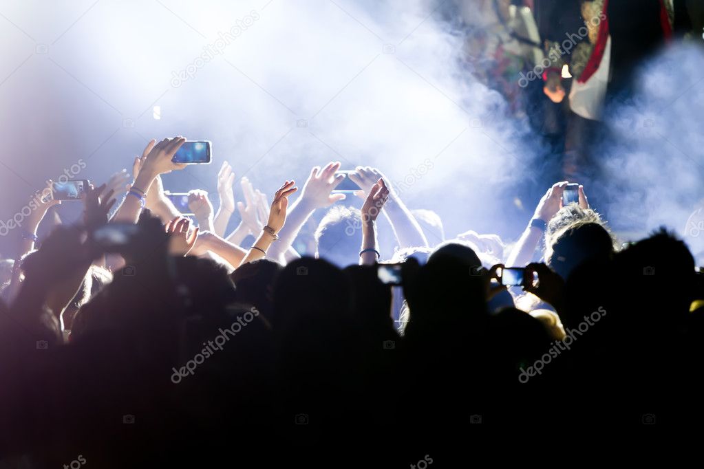 People taking photographs with touch smart phone during a music 