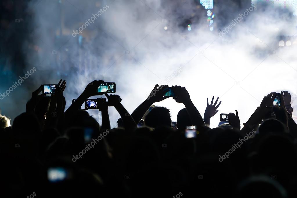 People taking photographs with touch smart phone during a music 