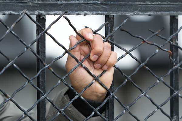 hand of a prisoner grabbed the bars of the prison