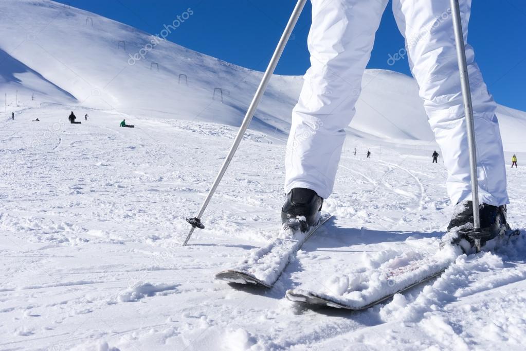 Close up of a skiers feet with ski poles.