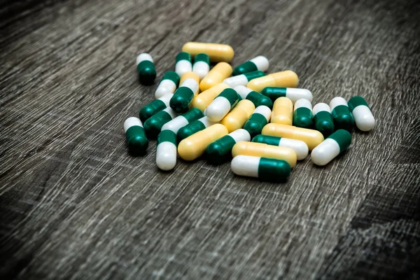 Muitas pílulas coloridas em um fundo de madeira . — Fotografia de Stock