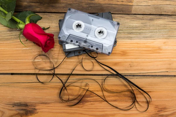 Rosa e cassete de áudio vintage em um fundo de madeira . — Fotografia de Stock