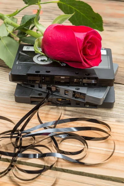 Rose and vintage audio cassette on a wooden background. — Stock Photo, Image