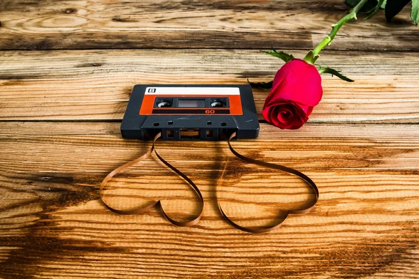 Rose and vintage audio cassette with loose tape shaping two hear — Stock Photo, Image