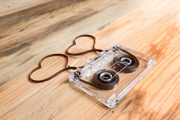 Vintage audio cassette with loose tape shaping two hearts on a w — Stock Photo, Image