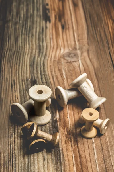 Lege houten naaien spoelen op oude hout achtergrond — Stockfoto