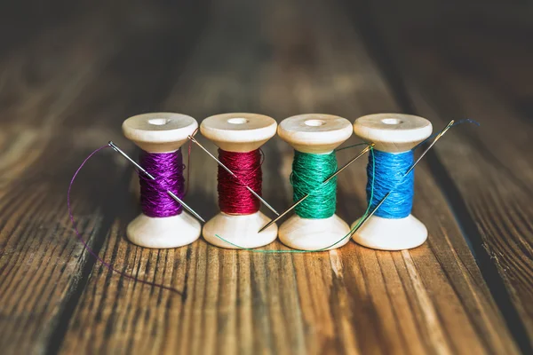 Spools of thread with needles on wooden background. Old sewing a — Stock Photo, Image