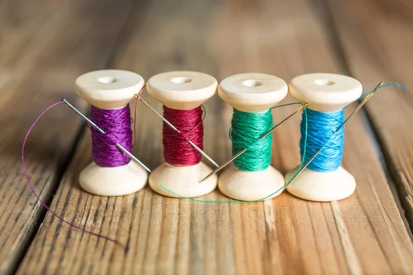 Spools of thread with needles on wooden background. Old sewing a — Stock Photo, Image