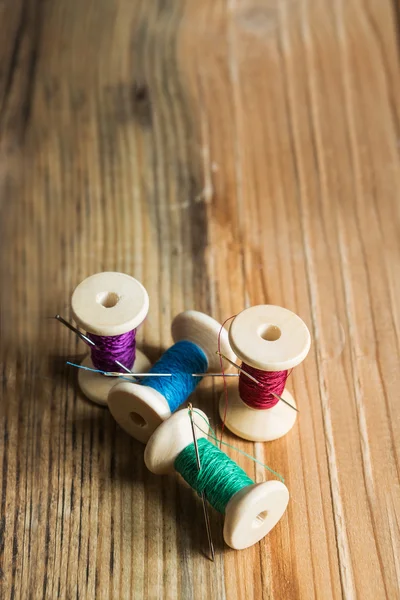 Bobinas de hilo con agujas sobre fondo de madera. Viejo coser un — Foto de Stock