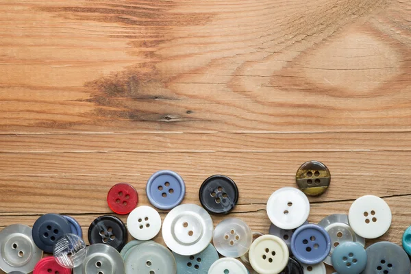 Barevná tlačítka na dřevěné desce, barevné knoflíky, na staré dřevěné — Stock fotografie