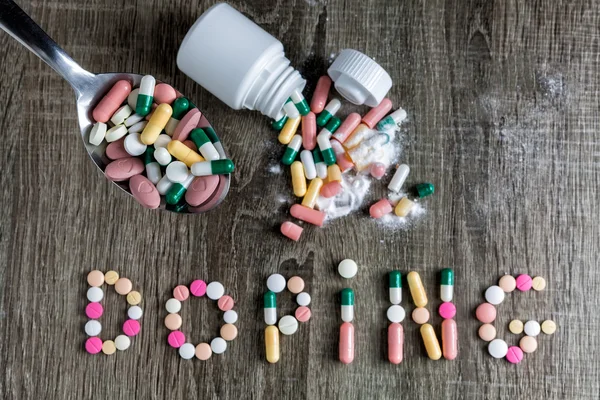 The word doping written with pills on a wooden background.