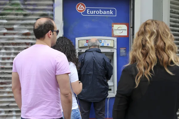 Mensen staan in een wachtrij te gebruiken van de geldautomaten van een bank — Stockfoto