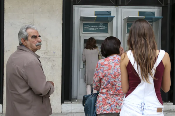 Mensen staan in een wachtrij te gebruiken van de geldautomaten van een bank — Stockfoto