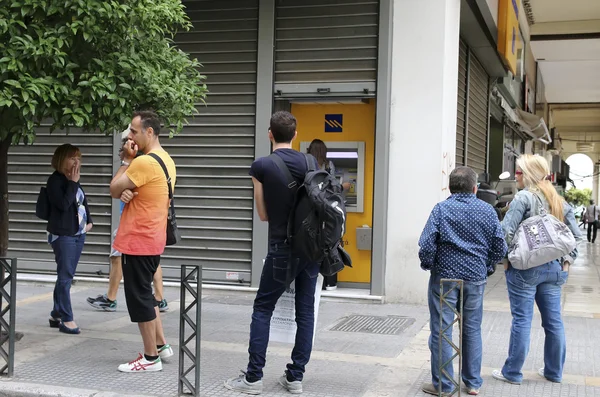 Люди стоят в очереди, чтобы воспользоваться банкоматами банка — стоковое фото