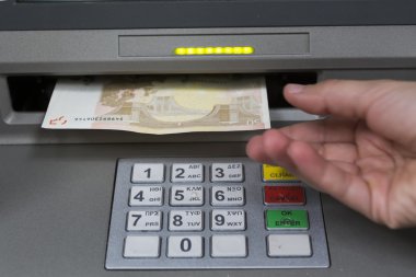 People stand in a queue to use the ATMs of a bank. Person receiv