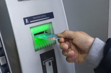 People stand in a queue to use the ATMs of a bank. Person receiv