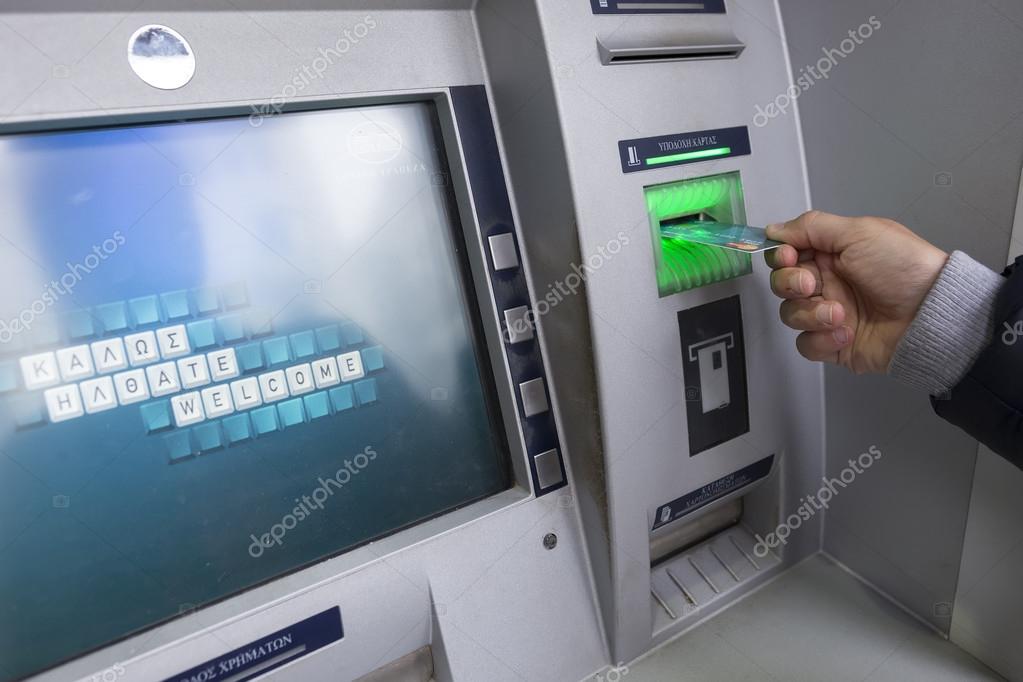 People stand in a queue to use the ATMs of a bank. Person receiv ...