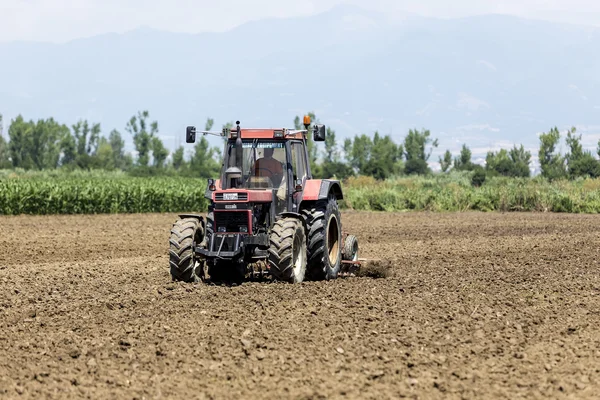 Pracovní Traktor pěstování pšenice v úrodné zemědělské oblasti G — Stock fotografie