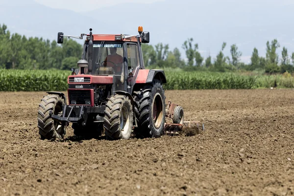 Un trattore che lavora piantando grano nei campi agricoli fertili di G — Foto Stock