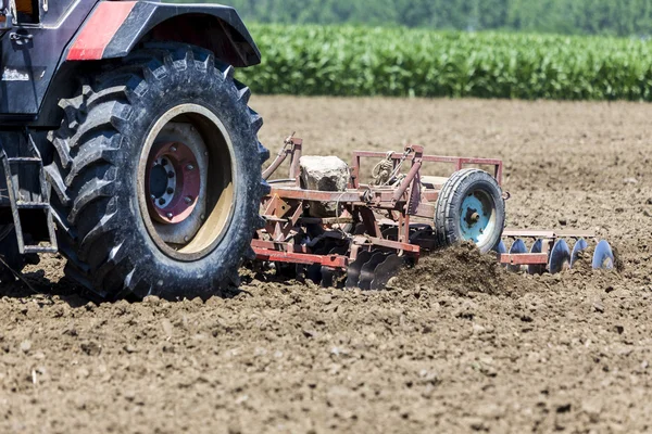 Pracovní Traktor pěstování pšenice v úrodné zemědělské oblasti G — Stock fotografie