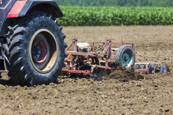 Un trattore che lavora piantando grano nei campi agricoli fertili di G — Foto Stock