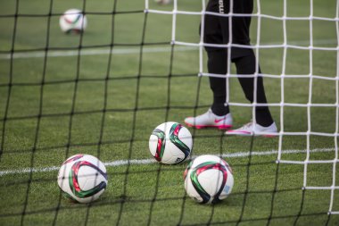 Balls of Paok team on the field of the stadium behind net during