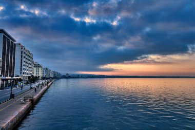 Selanik, Aristo Meydanı 'ndan denize doğru uzanır. Neoklasik zarafet, kıyı ritmiyle buluşur. Şehir yumuşak ve bulutlu bir gökyüzü altında tepelere doğru uzanır..