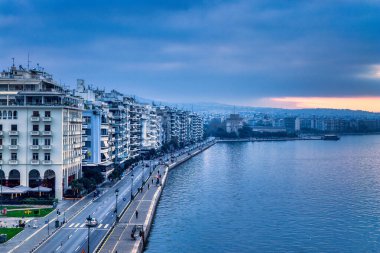 Selanik, Aristo Meydanı 'ndan denize doğru uzanır. Neoklasik zarafet, kıyı ritmiyle buluşur. Şehir yumuşak ve bulutlu bir gökyüzü altında tepelere doğru uzanır..