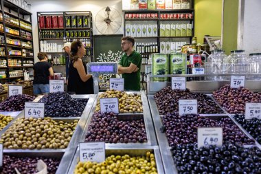 Selanik, Yunanistan, 17 Eylül 2025. Müşteriler Kapanis 'teki geleneksel yemek tezgahlarındaki metal tepsilerden zeytinleri karıştırıyor ve seçiyorlar.