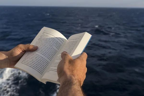 Handen met een boek op het dek van een schip. — Stockfoto