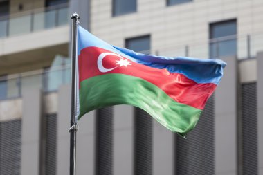 Bir binanın önünde rüzgarda sallayarak Azerbaycan bayrağı