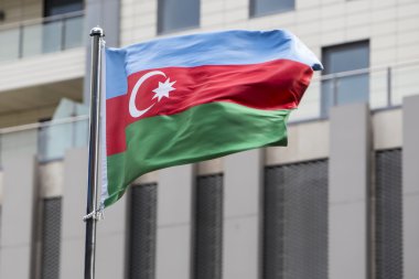 Bir binanın önünde rüzgarda sallayarak Azerbaycan bayrağı