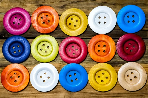 Цветные кнопки на деревянной доске, красочные кнопки, на старой деревянной — стоковое фото