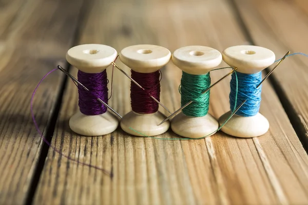 Spools of thread with needles on wooden background. Old sewing a — Stock Photo, Image