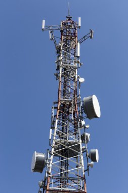 Mavi gökyüzüne karşı antenli iletişim kulesi