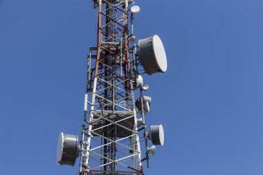 Mavi gökyüzüne karşı antenli iletişim kulesi