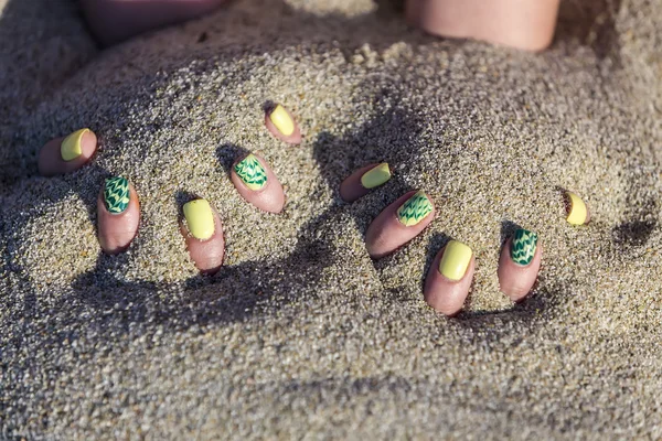 Main féminine avec beau vernis à ongles jouant avec le sable — Photo