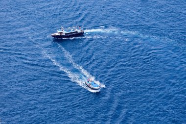 Yacht navigates into beautiful blue water near Santorini island, clipart