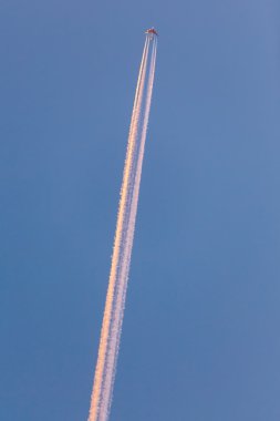 Gün batımında gökyüzünde yüksek contrail ile uçak