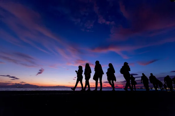 Die Silhouetten machen Aktivitäten am Strand bei Sonnenuntergang — Stockfoto