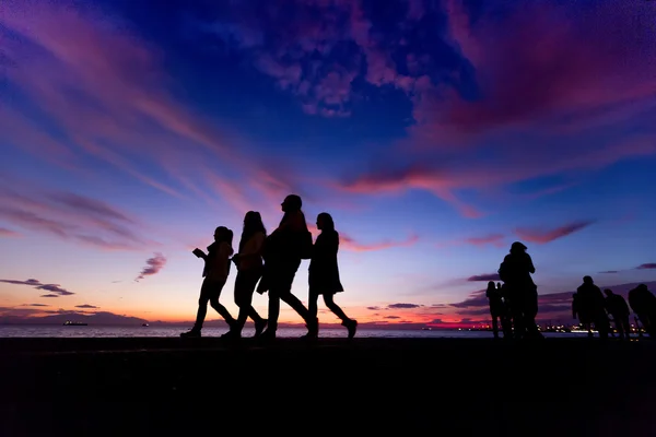 Die Silhouetten machen Aktivitäten am Strand bei Sonnenuntergang — Stockfoto