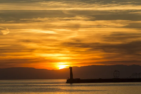 Zeegezicht bij zonsondergang. Vuurtoren aan de kust — Stockfoto