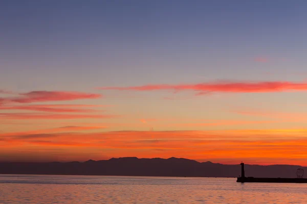 Zeegezicht bij zonsondergang. Vuurtoren aan de kust — Stockfoto