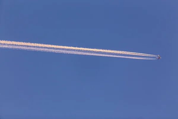 Airplane with contrail high in the sky at sunset — Stock Photo, Image