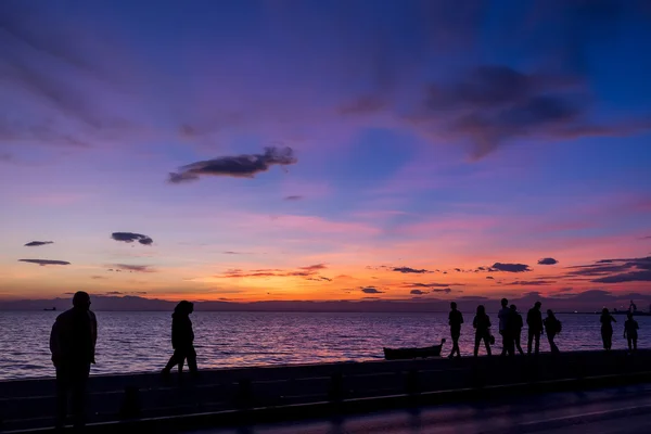 De silhouetten zijn het doen van activiteiten op het strand bij zonsondergang — Stockfoto