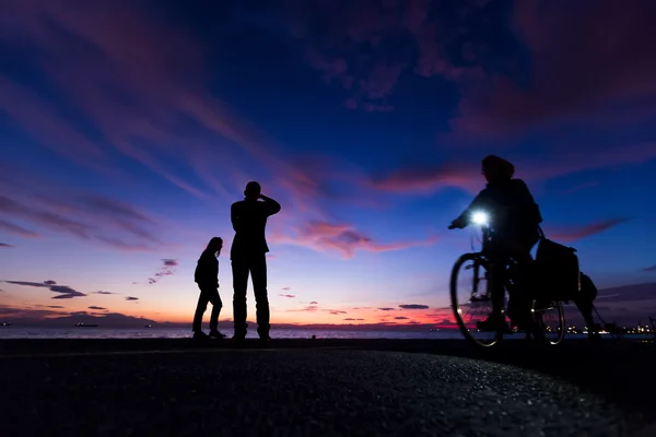 Die Silhouetten machen Aktivitäten am Strand bei Sonnenuntergang — Stockfoto