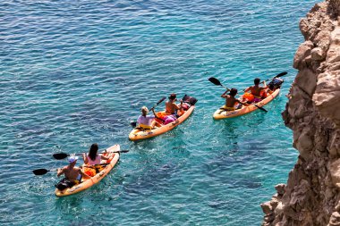 Tourists kayaking at Tsigrado Beach in Milos island, Cyclades, G clipart