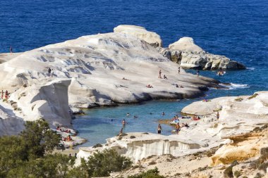 Tourists enjoy the clear water of Sarakiniko beach in Milos, Gre clipart