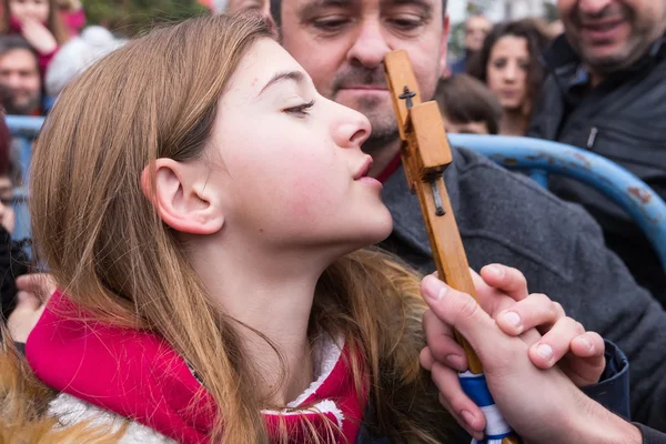 A child kisses a wooden cross retrieved from the sea during the — Stock Photo, Image